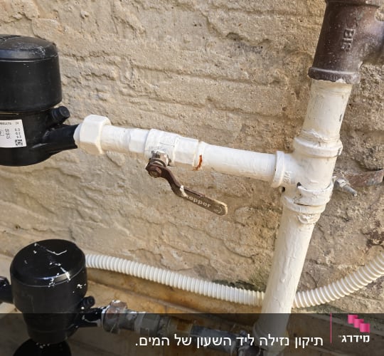 צנרת מים עם ברזים ומחברים על קיר חיצוני